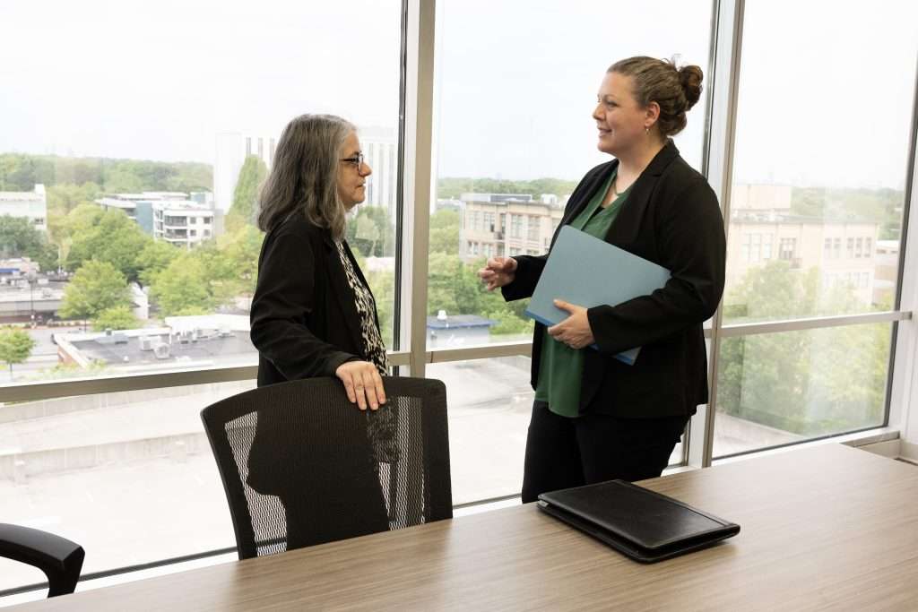 Kristen Howe having a conversation in a bright office with large windows.